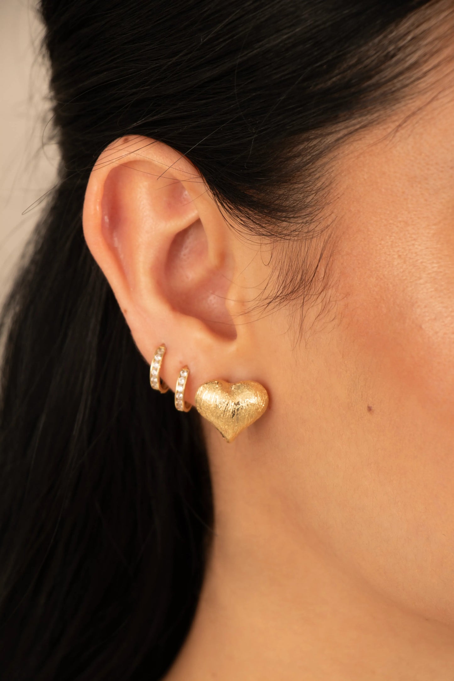 Arete corazón dorado texturizado en baño de oro 24K, fotografía de detalle para e-commerce.