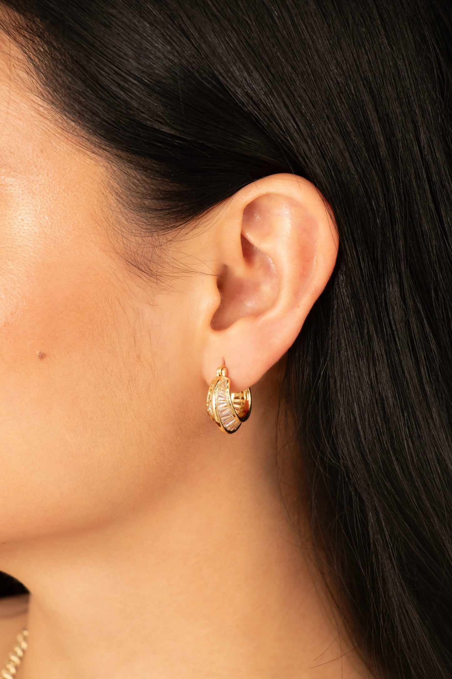 Candongas doradas texturizadas en baño de oro 24K, fotografía de detalle en oreja de modelo.