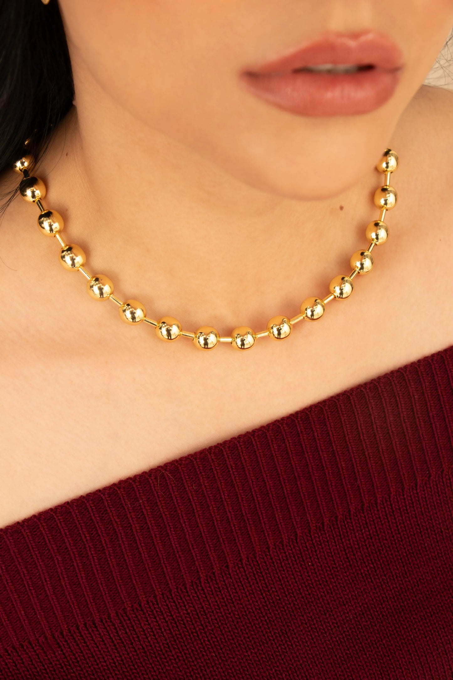 Collar de esferas doradas en baño de oro 24K, fotografía en el cuello de una modelo.