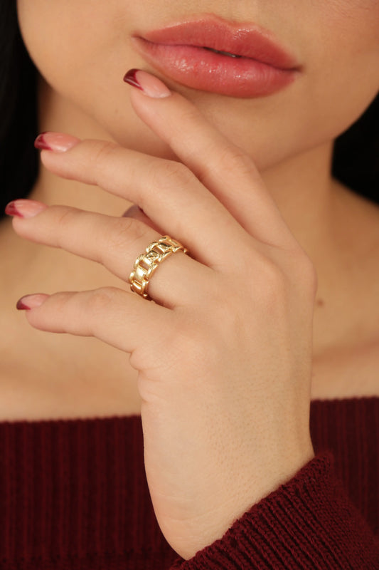 Anillo dorado tipo cadena ancha en baño de oro 24K, fotografía en mano de modelo.