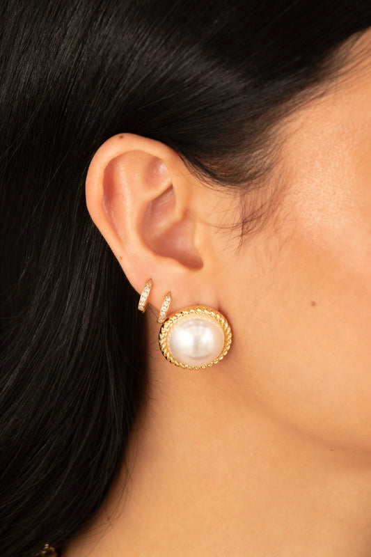 Aretes con perla grande y borde dorado trenzado en baño de oro 24K, fotografía de detalle en modelo.