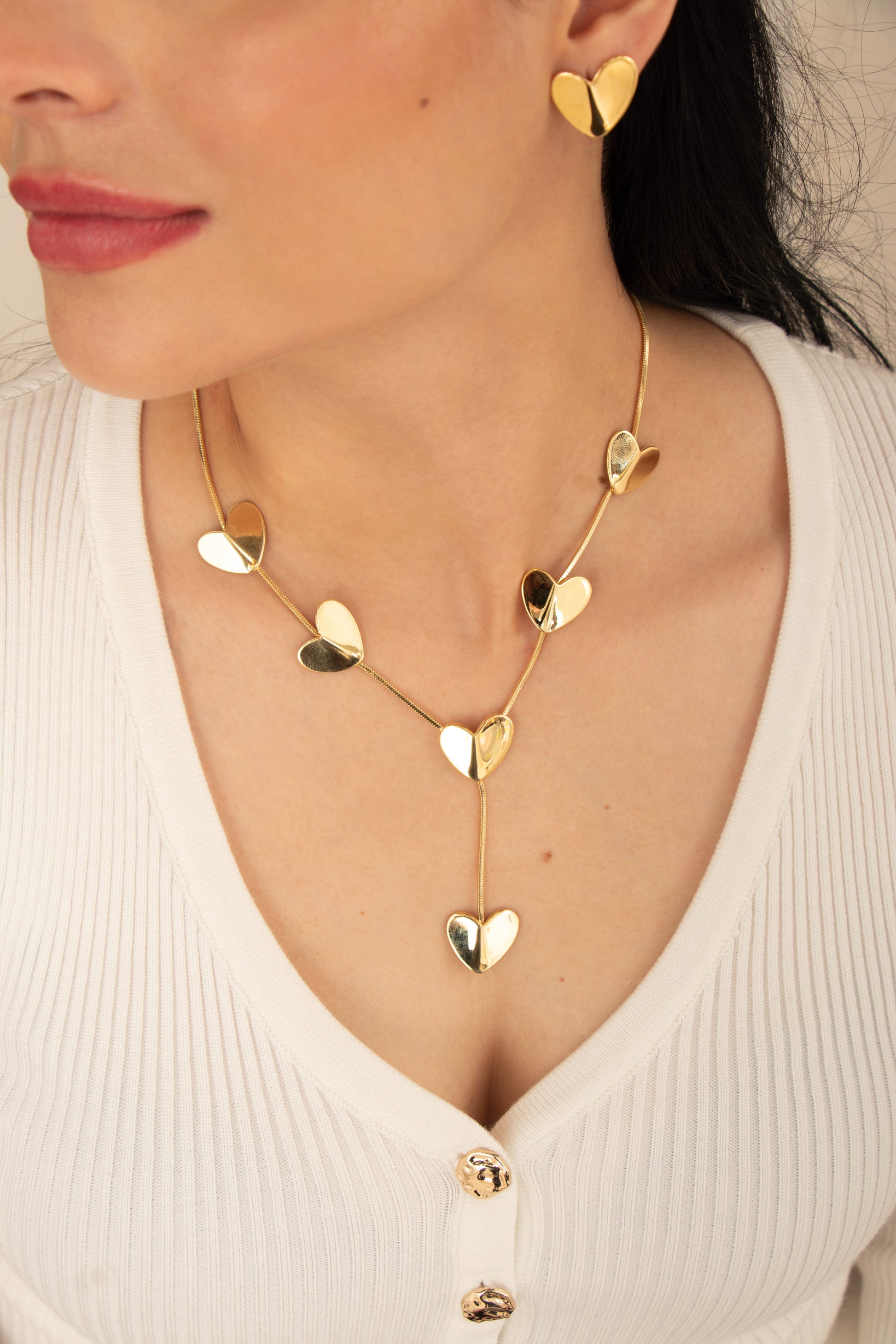 Collar dorado con múltiples corazones brillantes y diseño elegante que cae hacia el escote.