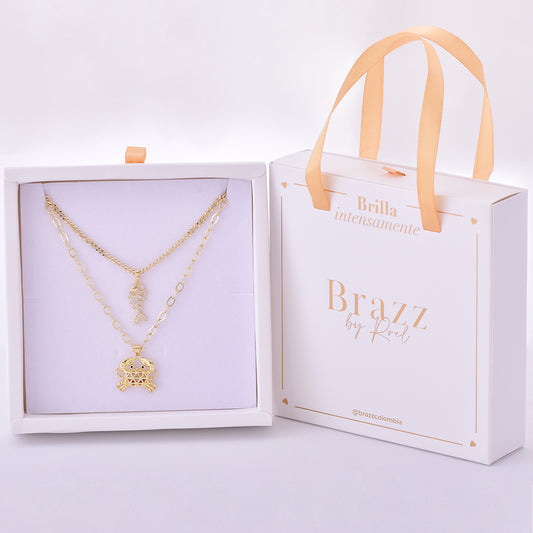Set de collares dorados con charm de pez articulado y cangrejo, presentado en caja Brazz by Roel.