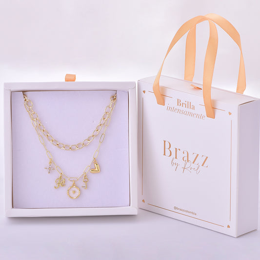 Set de collares dorados con dijes románticos como cruz, letra J, corazón, llave y charm circular, en caja Brazz by Roel.