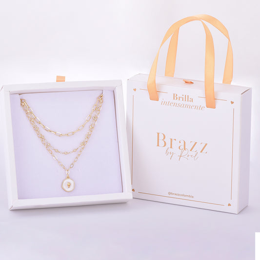 Set de collares en capas con medalla perlada y corazón dorado, presentado en caja de regalo Brazz by Roel.